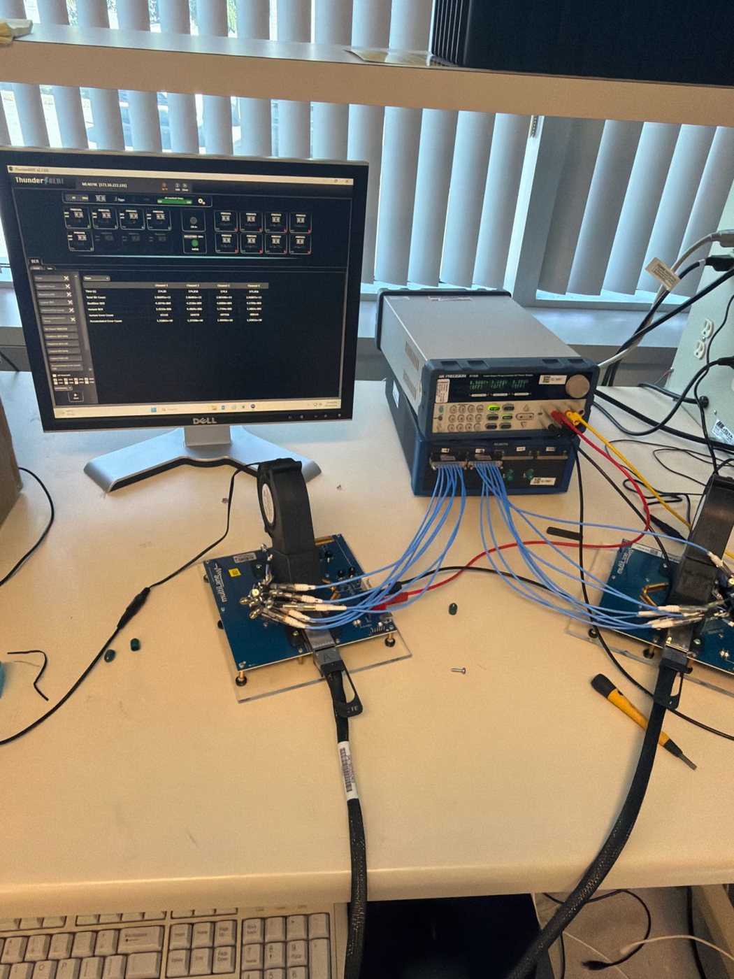 Evaluation boards connected with blue high-speed cables to test equipment